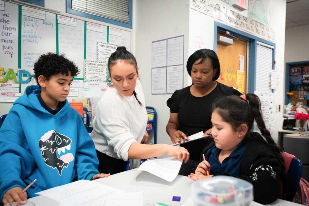 Two teachers lead their third-grade students through a math lesson
